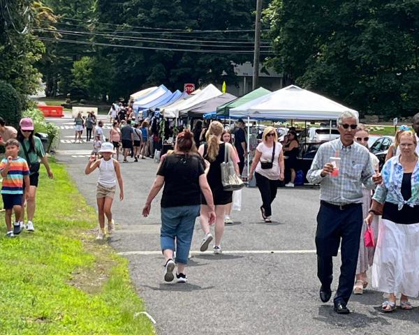 People walk along a row of vendor tents.
