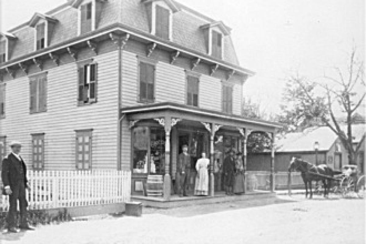 This is the Lloyd-McNomee store as it looked in the 1890s.  John Lloyd originally purchased it from Henry Bush in 1874 and formed a partnership with Lloyd Porter. In 1880 Albert McNomee became a partner forming the Lloyd-McNomee store until 1925 when it was sold to the Great Eastern Company with Thurman Rogers as manager.  Standing on the porch to the left is John and Lavina Sanders.  The Lloyd-McNomee Store today is an upholstery shop.  The mostly obscured building on the extreme right is Greenwood's Meat Store.