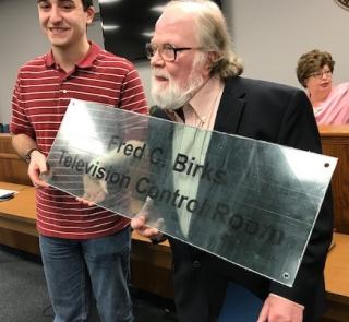 Fred Birks holds up sign bearing his name that will hang in the Control Room