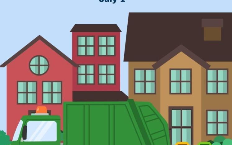 Garbage truck and recycling cans in front of houses on a street with blue sky in background.